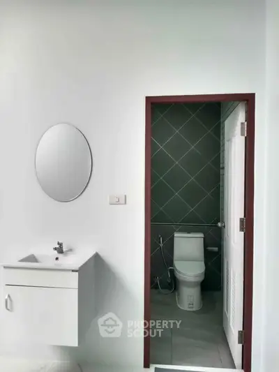 Modern bathroom with sleek design featuring a wall-mounted sink and a compact toilet.