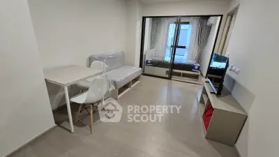 Modern studio apartment with sleek furnishings and large window for natural light.