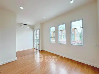 Bright and airy empty room with wooden flooring and large windows in modern home