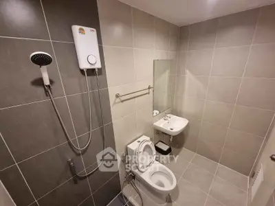 Modern bathroom with shower, toilet, and sink in sleek tile design.