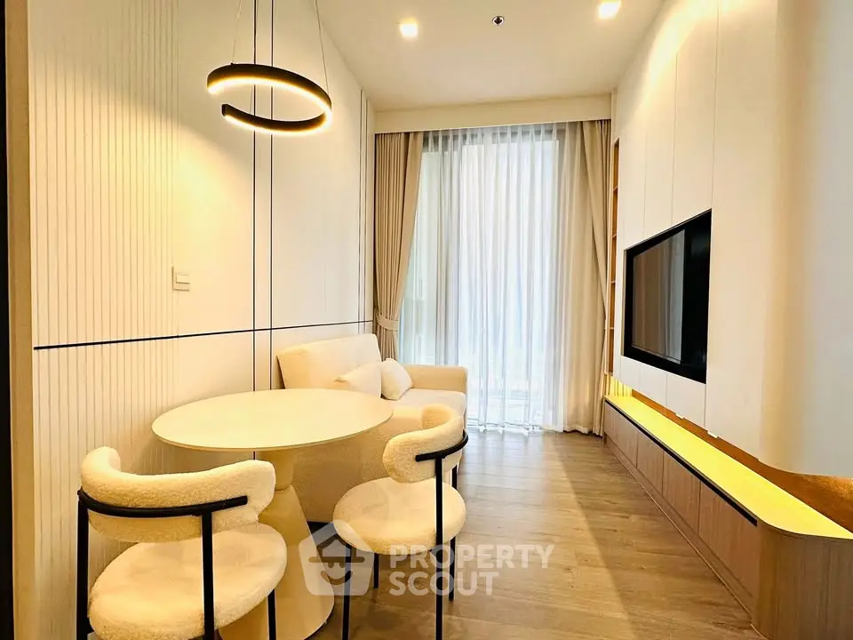 Modern living room with stylish furniture and large window, featuring a cozy seating area and elegant lighting.