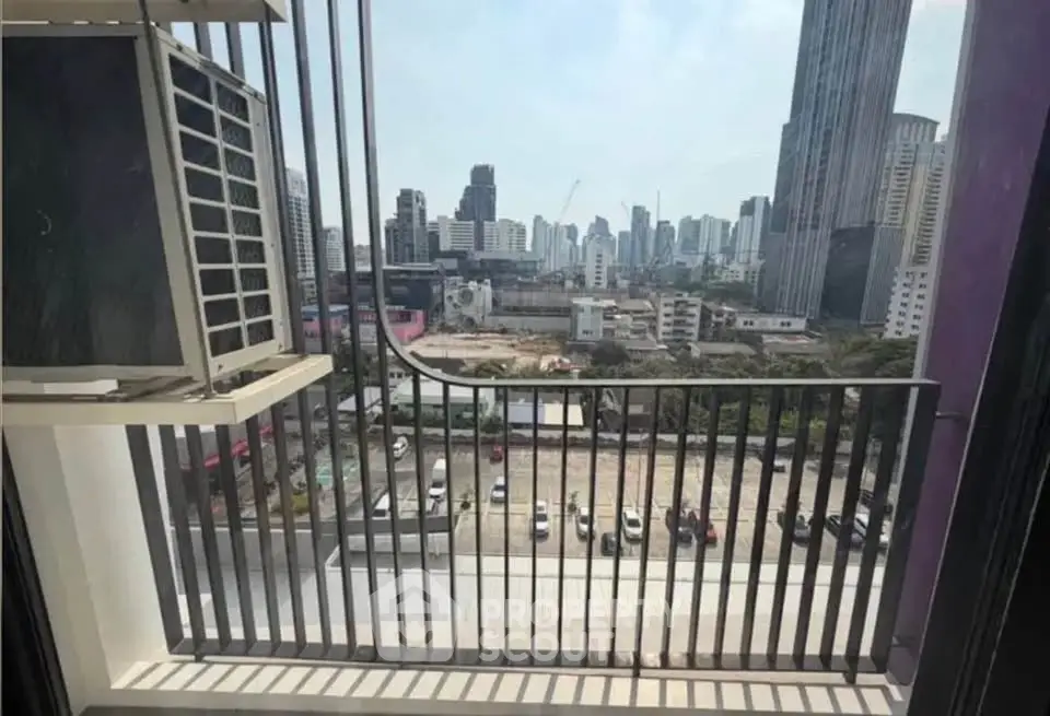City view from a high-rise balcony with urban skyline and parking lot below.