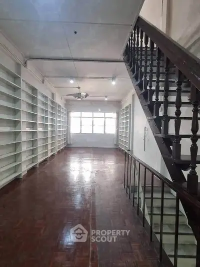 Spacious interior with wooden staircase and built-in shelves, ideal for library or study area.