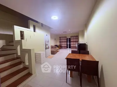 Spacious open-plan living area with modern staircase and dining set