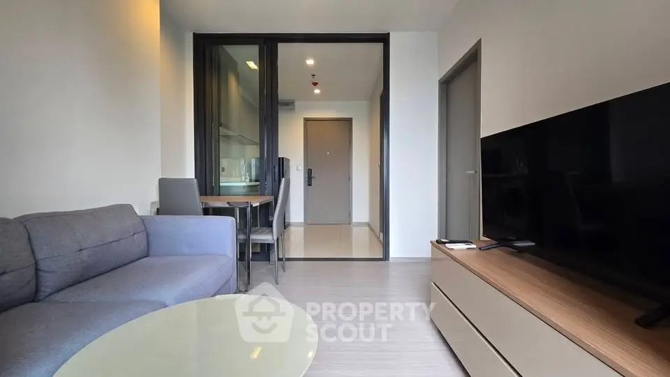 Modern living room with sleek furniture and open kitchen layout in a stylish apartment.