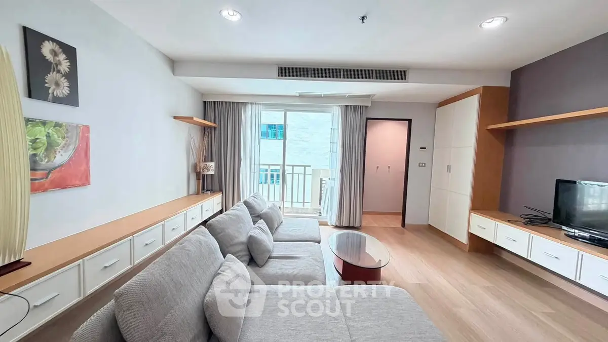 Spacious modern living room with cozy gray sofa and natural light from balcony.