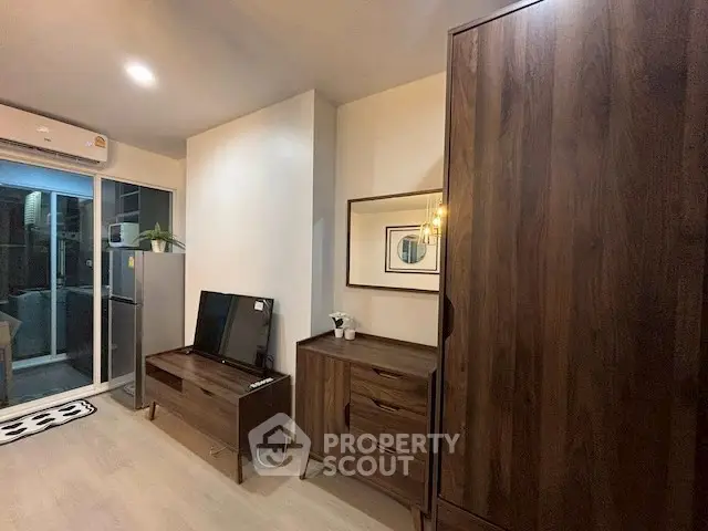 Modern living room with wooden furniture and sliding glass door to balcony.