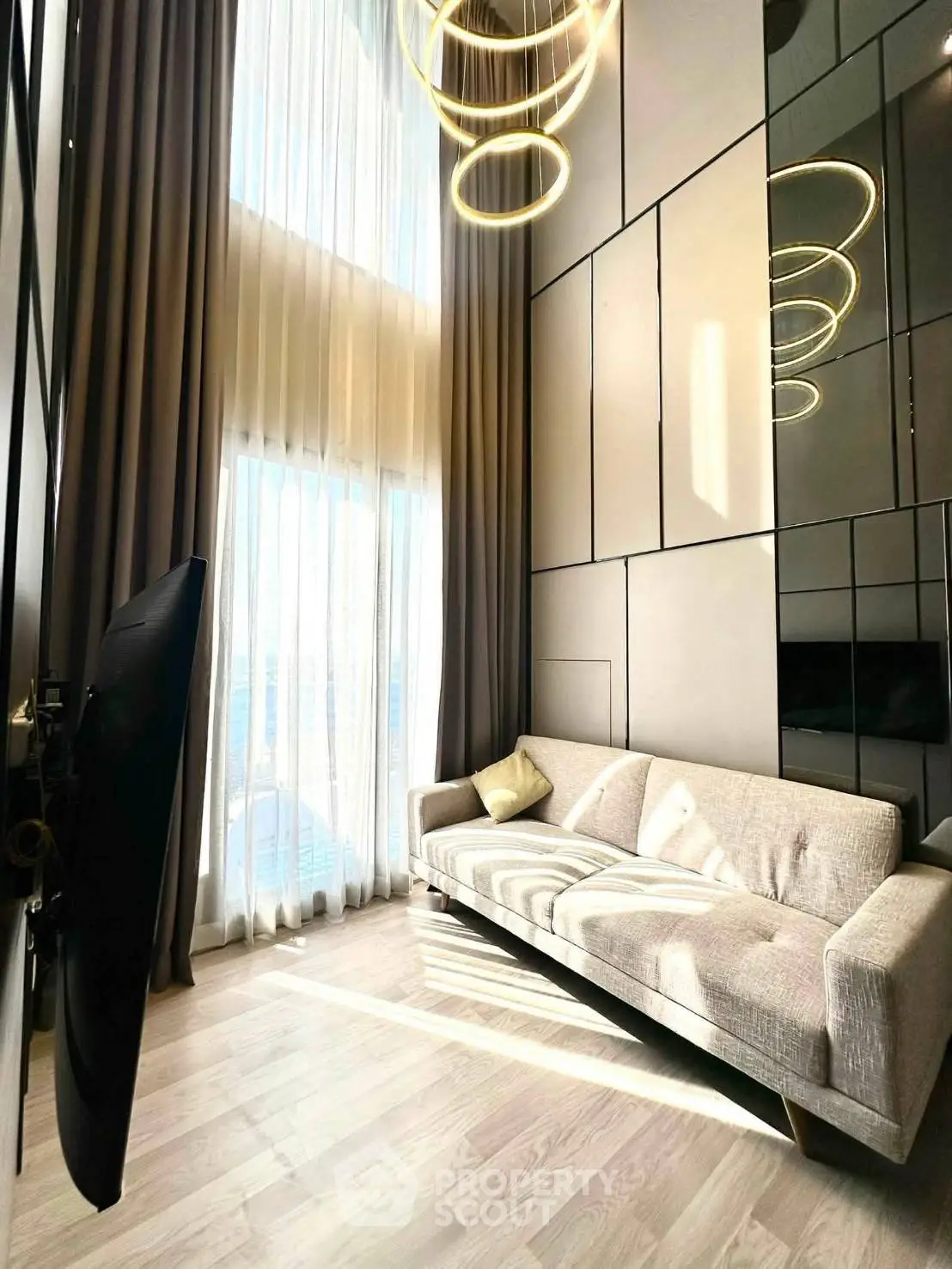 Luxurious high-ceiling living room with modern decor and large windows for natural light.