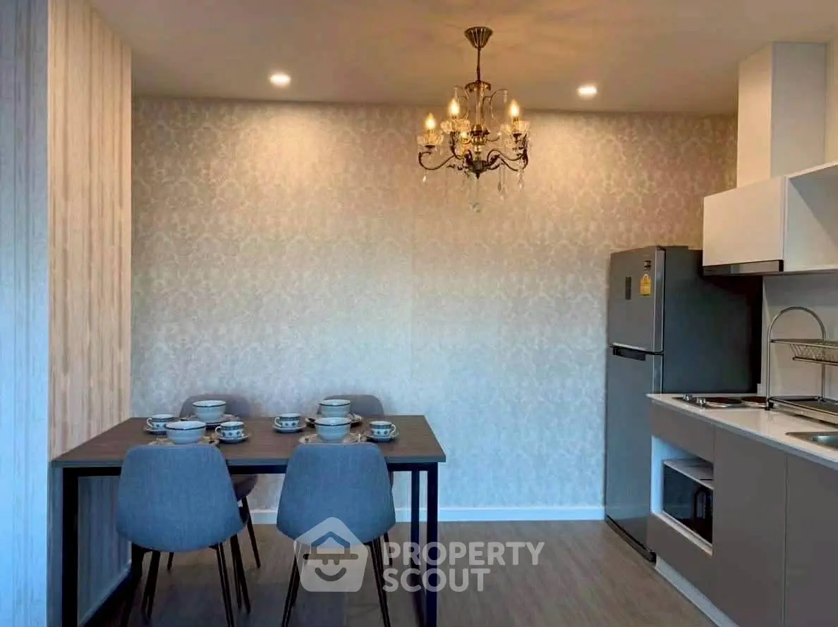 Modern kitchen with dining area, elegant chandelier, and sleek appliances.