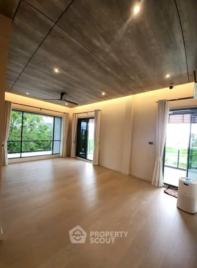 Spacious modern living room with large windows and wooden flooring