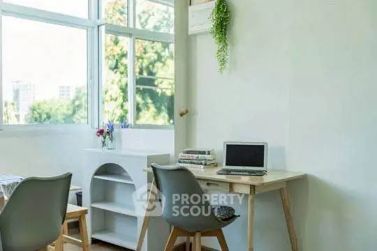Bright study area with modern desk and chairs, large windows, and greenery.