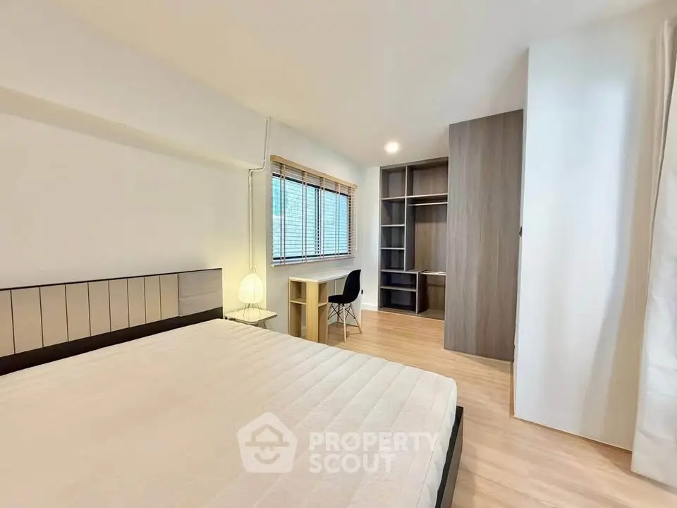 Spacious bedroom with modern furnishings and ample natural light, featuring a study area and large windows.