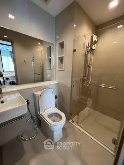 Modern bathroom with glass shower and sleek fixtures in contemporary apartment.