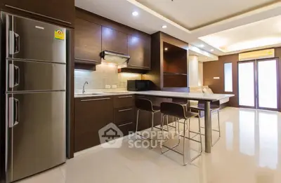 Modern kitchen with sleek design and open layout, featuring stainless steel appliances and stylish bar seating.