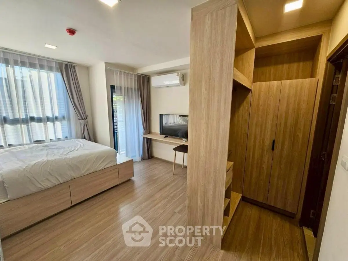 Modern bedroom with wooden flooring and built-in wardrobe, featuring natural light and sleek design.