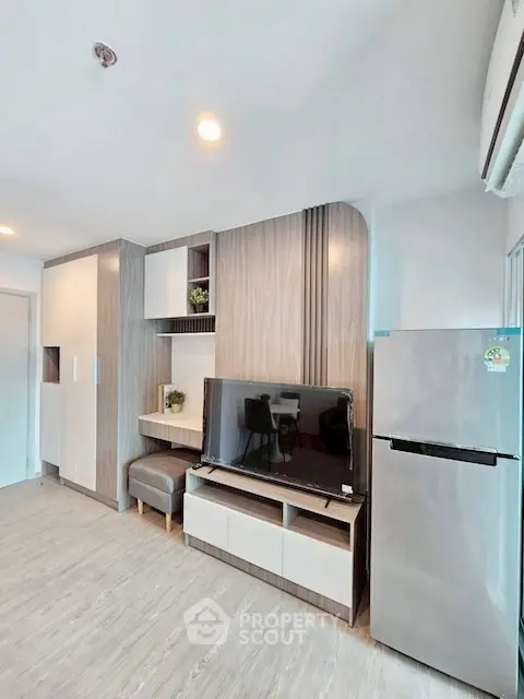 Modern living room with sleek furniture and stainless steel fridge, perfect for urban living.
