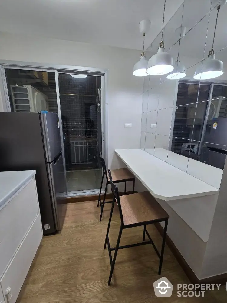 Modern kitchen with sleek design, featuring a breakfast bar and stylish lighting.