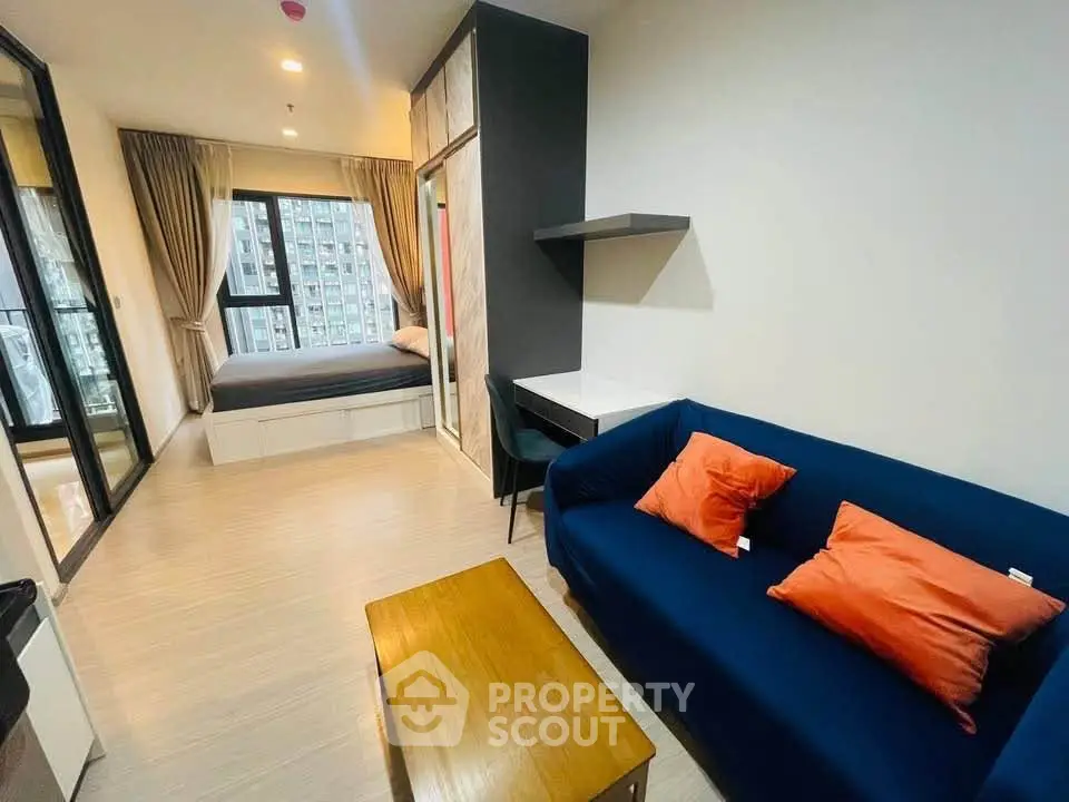 Modern studio apartment with cozy living area and bedroom, featuring stylish furniture and large windows.