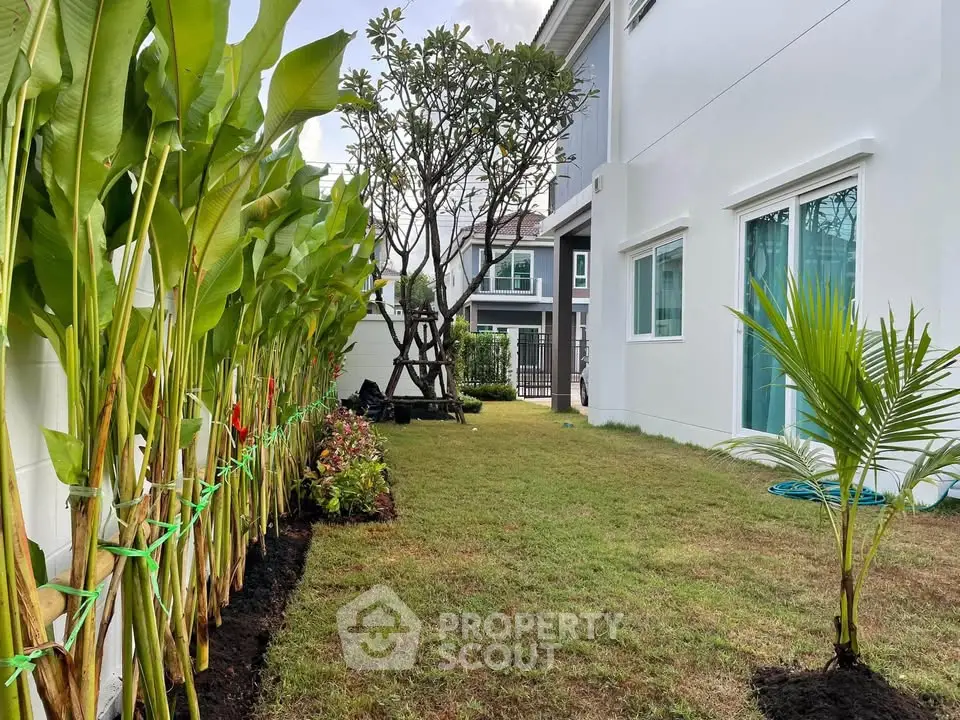 Charming garden view of modern home with lush greenery and spacious lawn, perfect for outdoor relaxation.