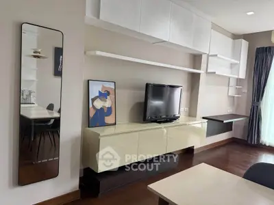 Modern living room with sleek cabinetry and wall-mounted TV, featuring stylish decor and natural light.