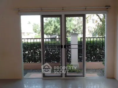 Spacious room with sliding glass doors opening to a lush garden view, perfect for natural light lovers.