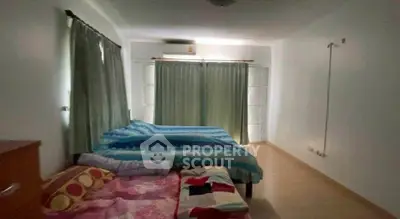 Spacious bedroom with large windows and cozy bedding in a modern home.