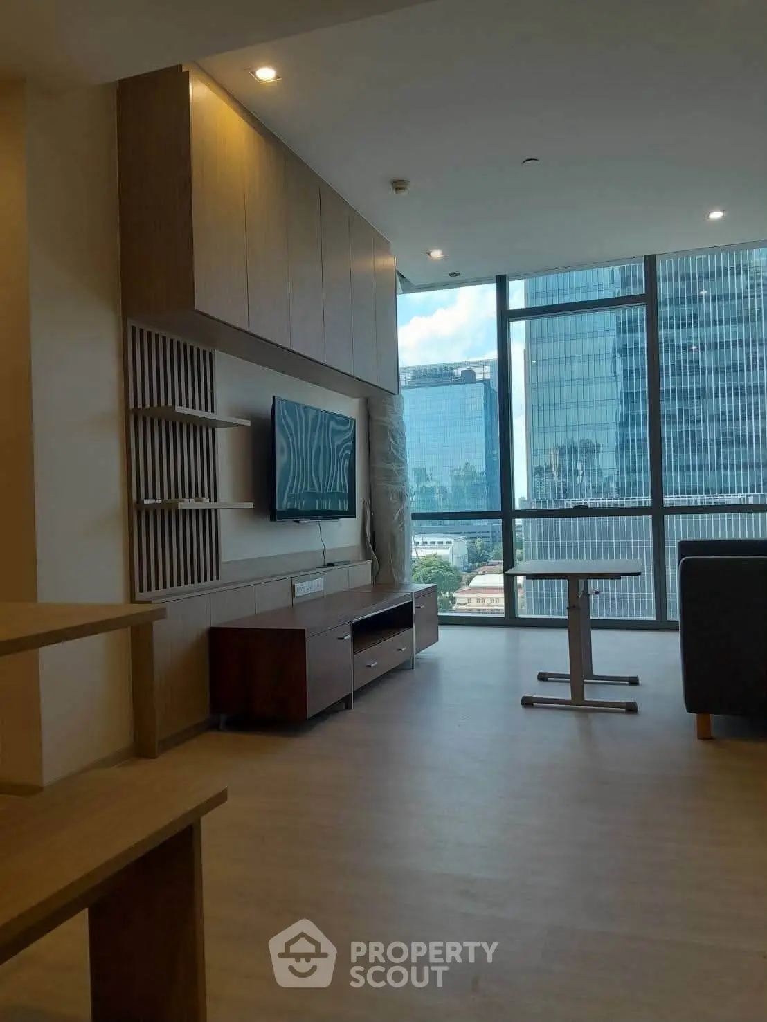 Modern living room with large windows offering stunning city views, featuring sleek furniture and elegant design.