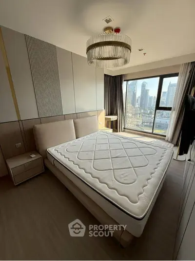 Modern bedroom with large window offering stunning city view, featuring elegant chandelier and stylish decor.