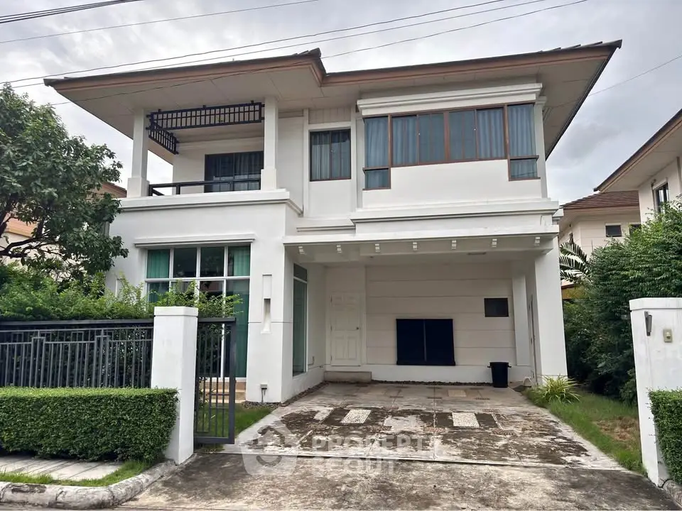 Elegant two-story white house with lush greenery and spacious driveway in a serene neighborhood.