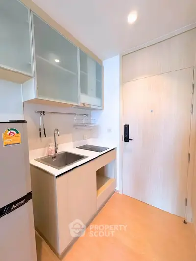 Modern compact kitchen with sleek cabinetry and dual sinks in a stylish apartment.