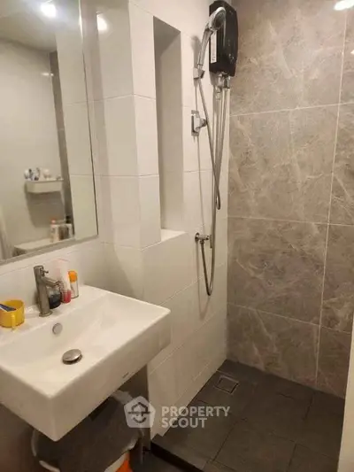 Modern bathroom with sleek shower and stylish sink in contemporary apartment.