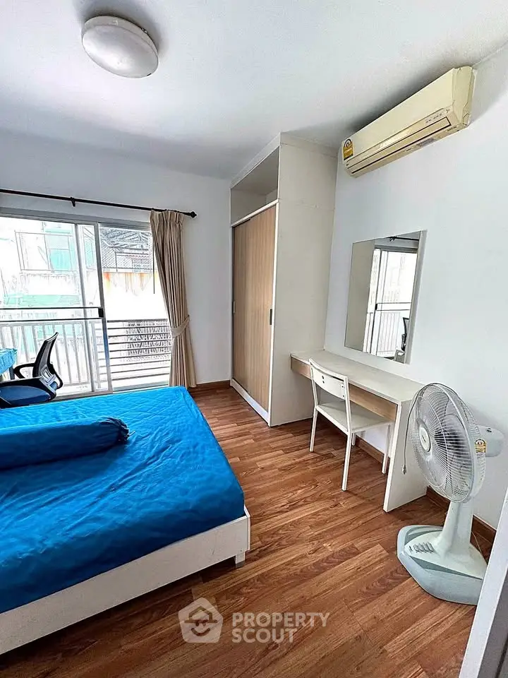 Bright bedroom with wooden flooring, large window, and modern furniture in a stylish apartment.