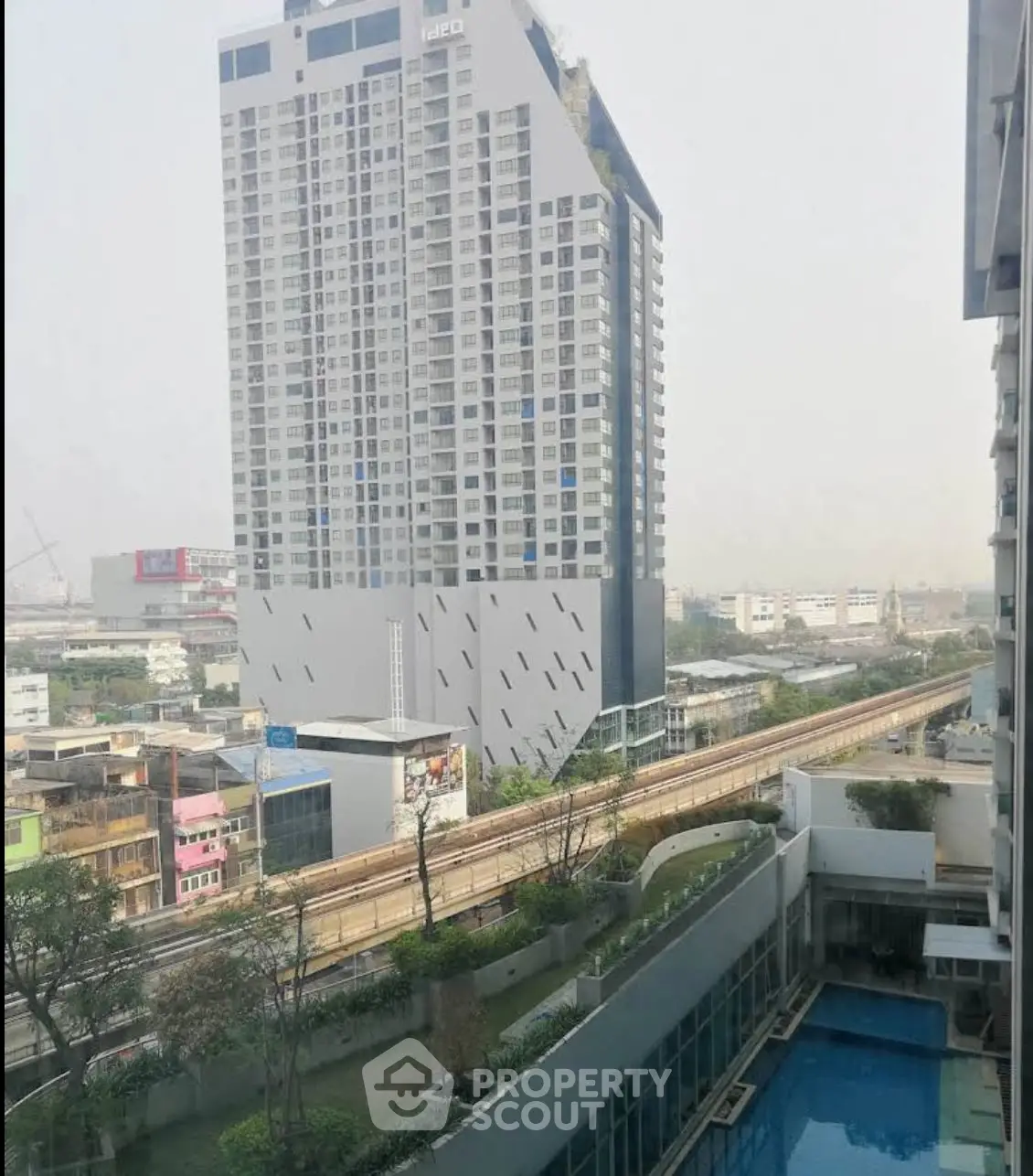 Stunning cityscape view from high-rise apartment with pool and modern architecture.
