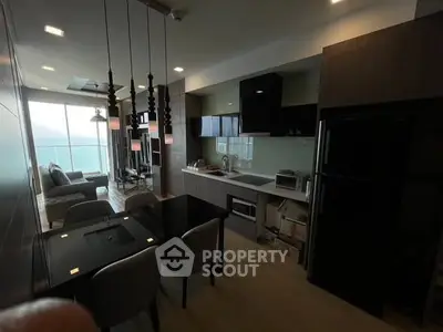Modern open-layout kitchen and living room with stylish decor and large windows offering natural light.