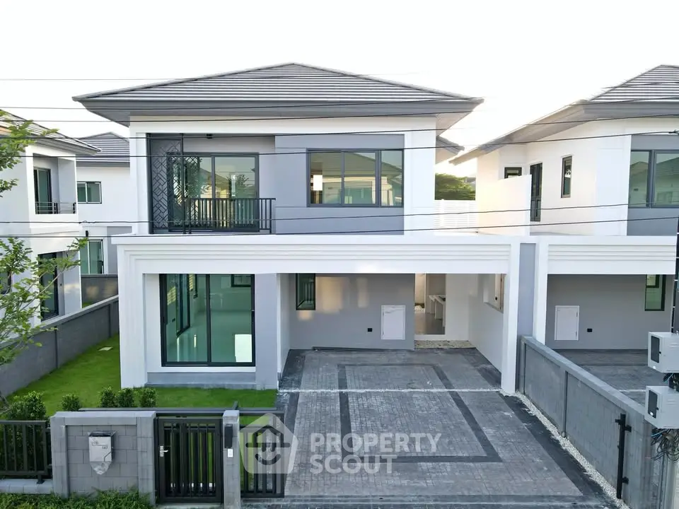 Modern two-story house with sleek design and spacious driveway in a suburban neighborhood.