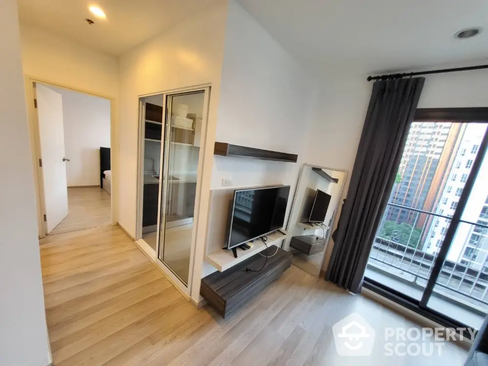 Modern living room with TV and balcony view in high-rise apartment