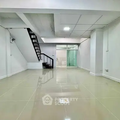 Spacious interior with modern staircase and glossy tiled flooring, ideal for versatile living space.