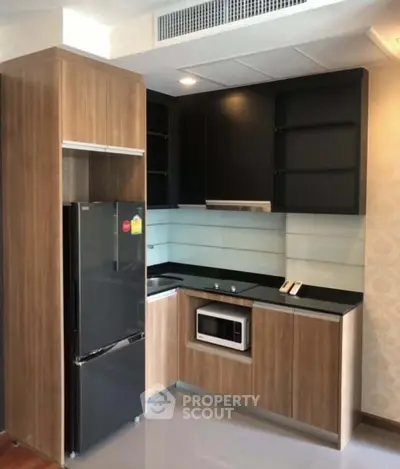 Modern kitchen with sleek black appliances and wooden cabinetry in a stylish apartment.