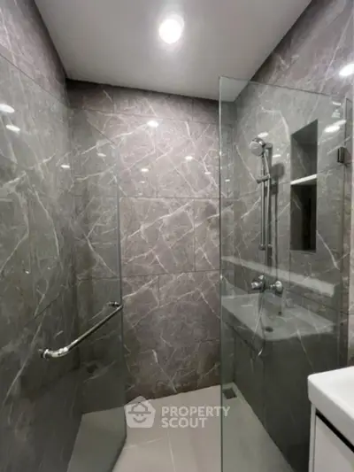 Modern bathroom with glass shower enclosure and marble walls