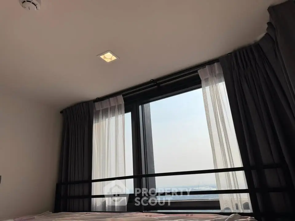 Cozy bedroom with large window offering stunning sea view and ample natural light.