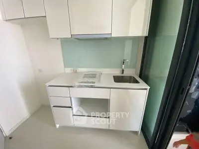 Modern compact kitchen with sleek white cabinetry and stainless steel sink