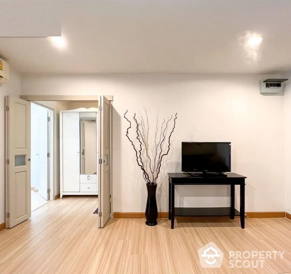 Spacious and well-lit living room with sleek hardwood floors, modern lighting, and a minimalist decor, perfect for urban living.