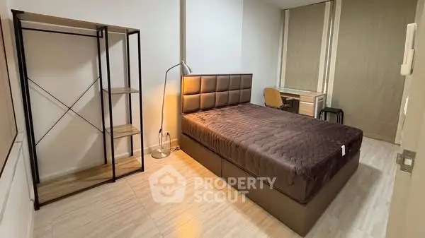Modern bedroom with stylish bed, open shelving, and cozy workspace