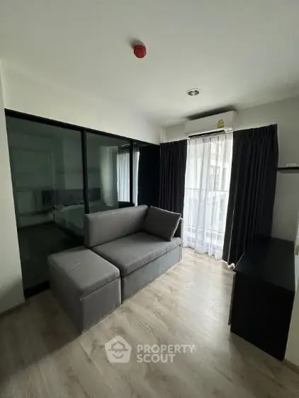 Modern living room with sleek gray sofa and large window for natural light.