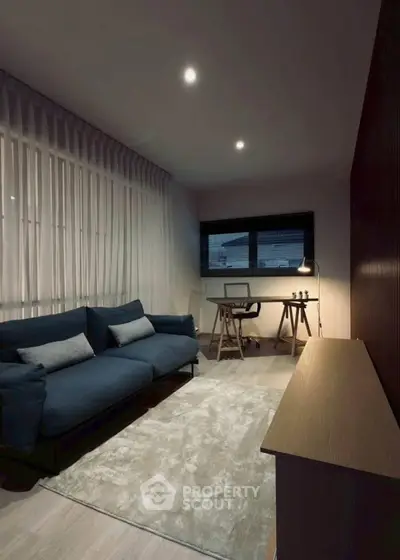 Modern living room with stylish sofa and work desk, perfect for cozy evenings.