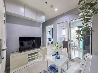 Modern living room with TV, stylish decor, and balcony view in a contemporary apartment.