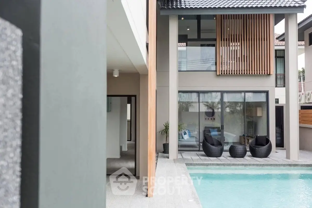 Modern luxury home with poolside view and stylish outdoor seating area.