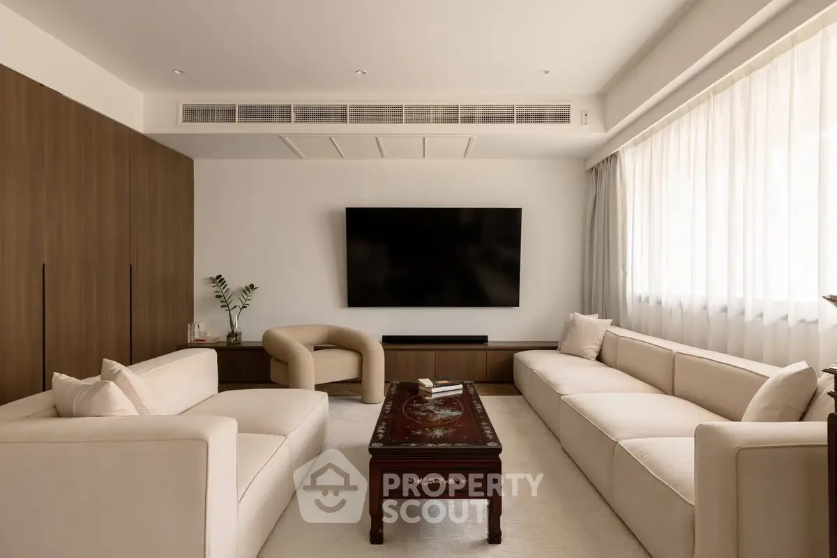 Elegant living room with modern furniture and large TV, perfect for relaxation and entertainment.