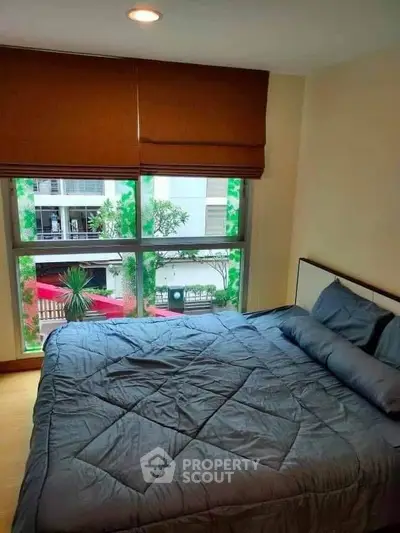 Cozy bedroom with large window offering natural light and urban view.