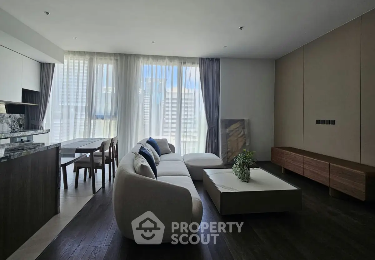 Spacious modern living room with elegant furniture and large windows offering city views.